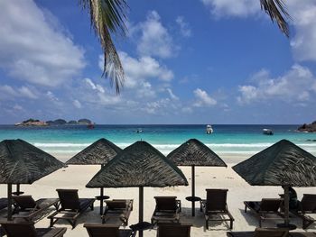 Deck chairs on beach against sky