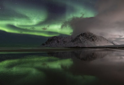 Scenic view of lake by mountain against sky at night