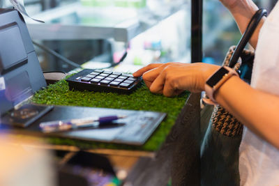 Woman costomer enters the amount into the cash register in cafe