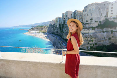 Attractive young tourist woman walking in tropea village on coast of the gods, calabria, italy.