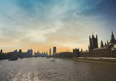 View of river and buildings against sky during sunset