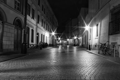 People on illuminated street amidst buildings at night