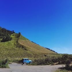 Car on road against clear blue sky