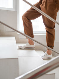 Woman in white sneakers and khaki trousers goes upstairs to her apartment. casual outfit, fashion.