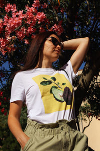 Young woman looking down while standing against plants