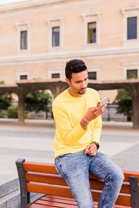 Young man using phone while sitting outdoors