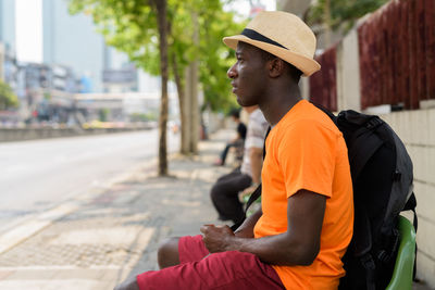 Side view of man sitting on street in city