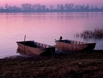 Boat moored on shore against sky during sunset