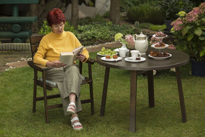 Senioren woman sitting in the garden and reading a book 