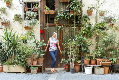 Woman standing by potted plants in yard