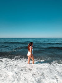 Woman standing in sea against clear sky