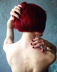 Rear view of topless woman with redhead against wall