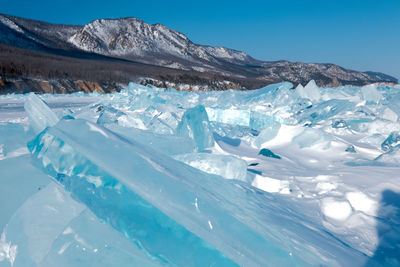 Pieces of crystal clear lake ice with mountains in background