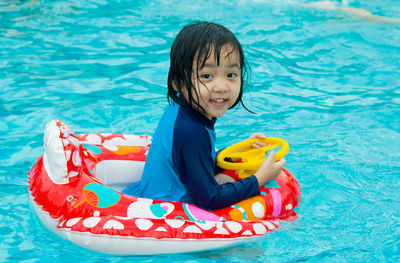 Portrait of smiling girl with inflatable ring in pool