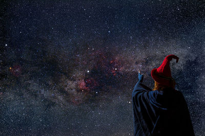 A strange woman in a red hat looks at the starry sky