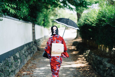 Full length of woman with umbrella walking in rain