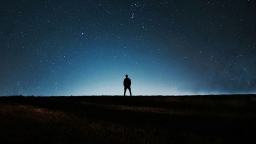 Silhouette man standing on field against clear sky at night