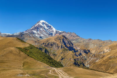 Scenic view of mountains against clear blue sky