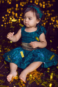Girl in blue dress in studio with gold sequins and garland