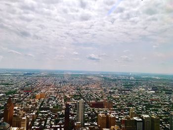 Aerial view of cityscape against cloudy sky