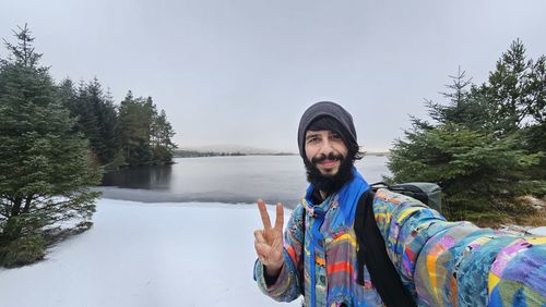 Portrait of young woman standing against trees