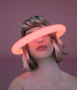 Portrait of woman standing against pink background