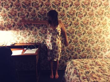 Full length of woman standing against patterned wall at home