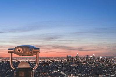 Coin-operated binoculars against cityscape against sky