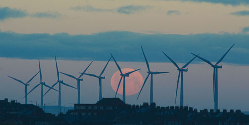 Wind turbines against sky during moonset