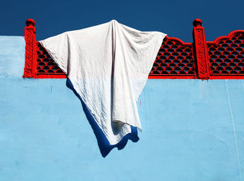 Low angle view of fabric hanging from red railing at building terrace