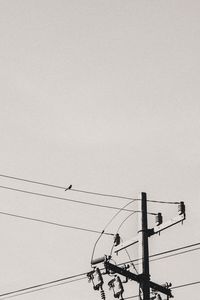 Low angle view of electricity pylon against clear sky