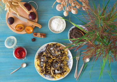 High angle view of sweet pasta dessert, noodles with poppy seeds on blue background table.