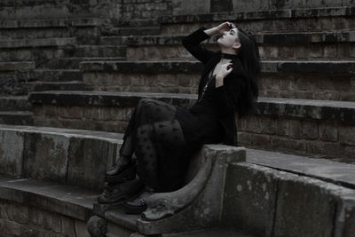 Side view of woman sitting on staircase