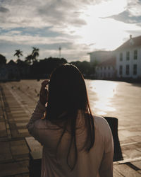 Rear view of woman standing against sky during sunset