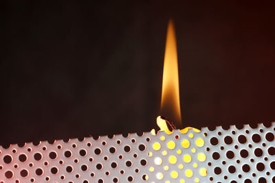 Close-up of illuminated candles on metal