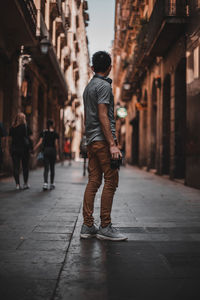 Rear view of man walking on street amidst buildings