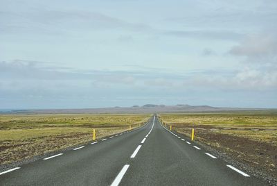 Empty road along landscape against sky