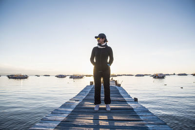 Man standing on pier over sea against clear sky