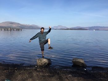 Full length of woman standing on cliff by sea