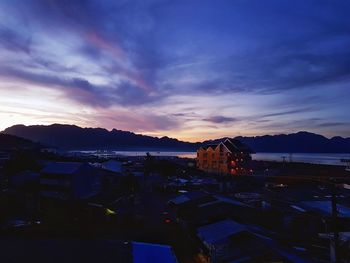 High angle view of buildings by sea against sky at sunset