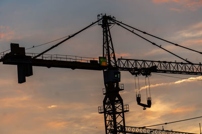 Low angle view of silhouette crane against sky during sunset