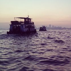 Boats in sea at sunset