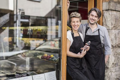 Portrait of confident workers standing at supermarket entrance