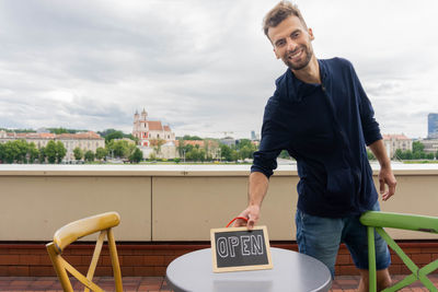 Young man smiling while standing against railing