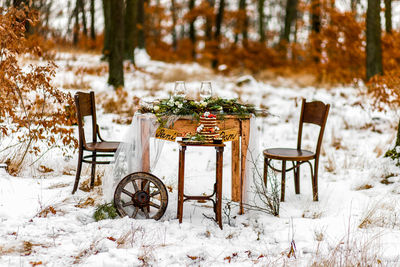 Close-up of small table and chairs on snow covered land