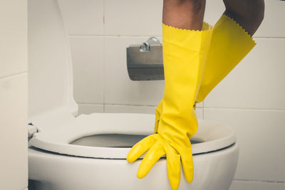 Cropped hands cleaning toilet bowl in bathroom