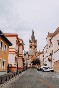 Road amidst buildings in city against sky