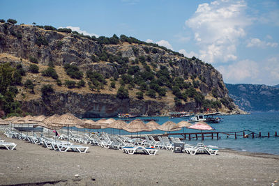 Sunbeds with umbrellas on gray sand on an empty beach with a mountain