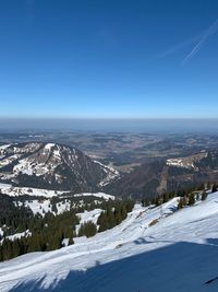 Scenic view of snowcapped mountains against clear blue sky