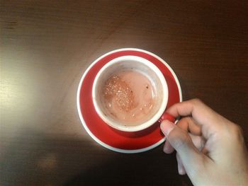 Cropped image of person holding coffee cup on table